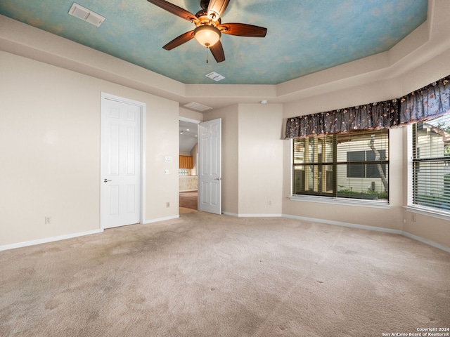 carpeted spare room featuring a tray ceiling and ceiling fan