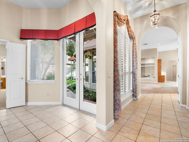 doorway to outside featuring light tile patterned flooring and an inviting chandelier