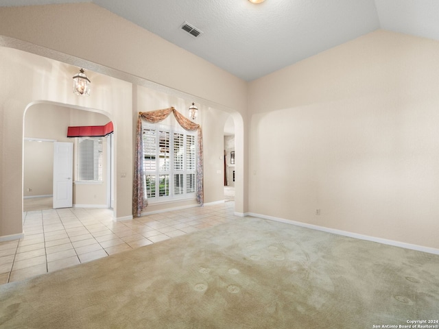 carpeted empty room with vaulted ceiling