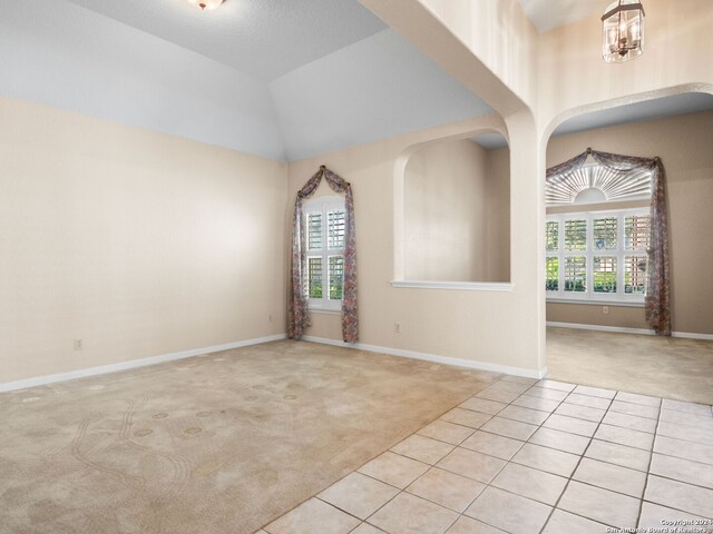 unfurnished room with a chandelier, light carpet, a healthy amount of sunlight, and a textured ceiling