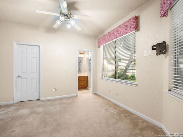 unfurnished bedroom with connected bathroom, light carpet, and ceiling fan