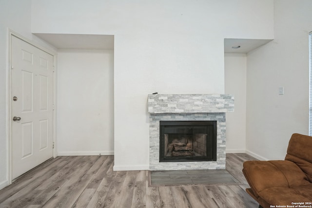 unfurnished living room featuring a stone fireplace and light wood-type flooring