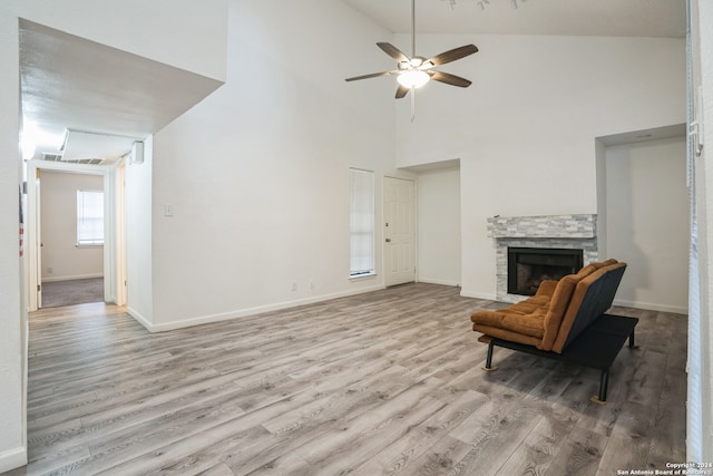 living area featuring ceiling fan, a fireplace, high vaulted ceiling, and light hardwood / wood-style floors