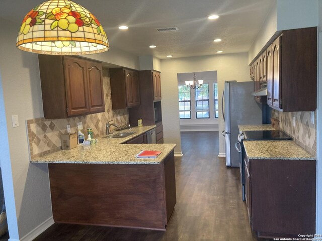 kitchen featuring light stone countertops, kitchen peninsula, dark hardwood / wood-style flooring, backsplash, and a notable chandelier