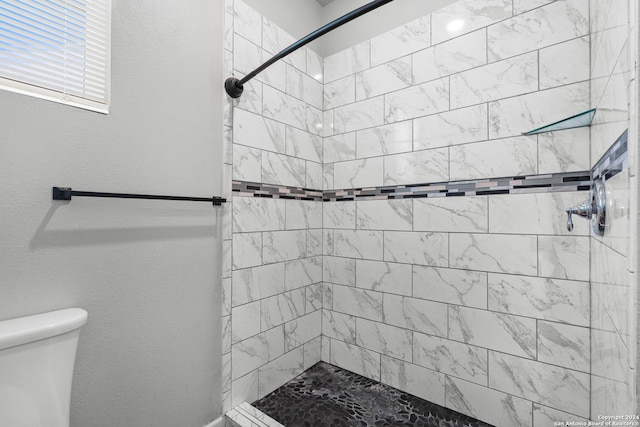 bathroom featuring tiled shower and toilet