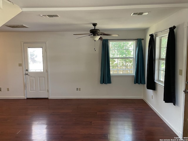 empty room featuring plenty of natural light, ceiling fan, and dark hardwood / wood-style flooring