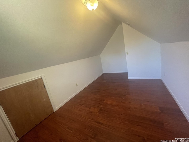 bonus room with dark wood-type flooring and vaulted ceiling