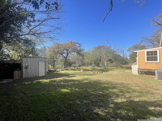 view of yard with central air condition unit and a storage shed