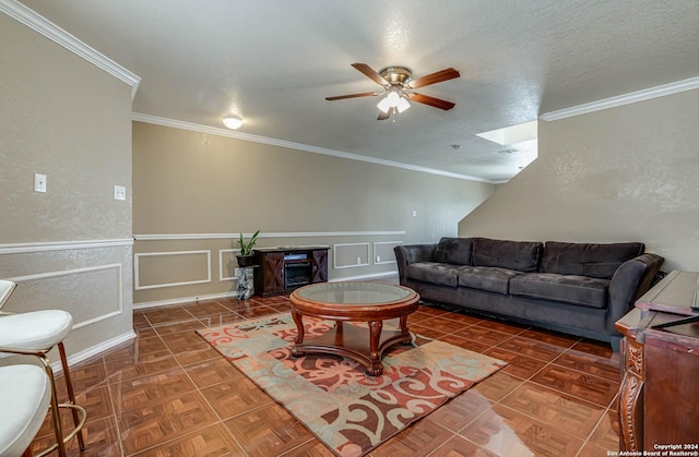 living room featuring crown molding, ceiling fan, and a textured ceiling