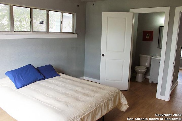 bedroom with ensuite bathroom and hardwood / wood-style flooring