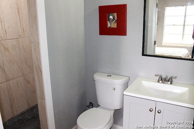 bathroom featuring a tile shower, vanity, and toilet