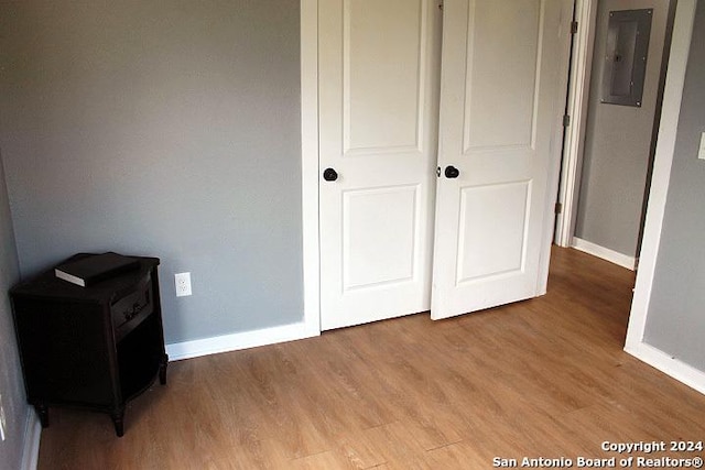 unfurnished bedroom with electric panel and light wood-type flooring