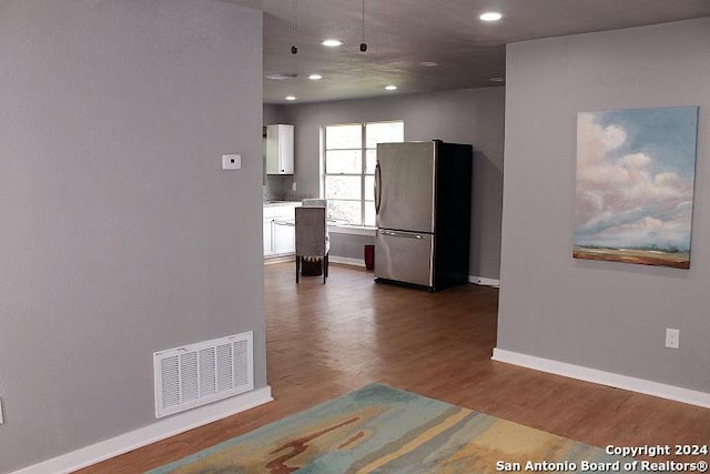 kitchen featuring hardwood / wood-style floors, stainless steel fridge, and white cabinetry