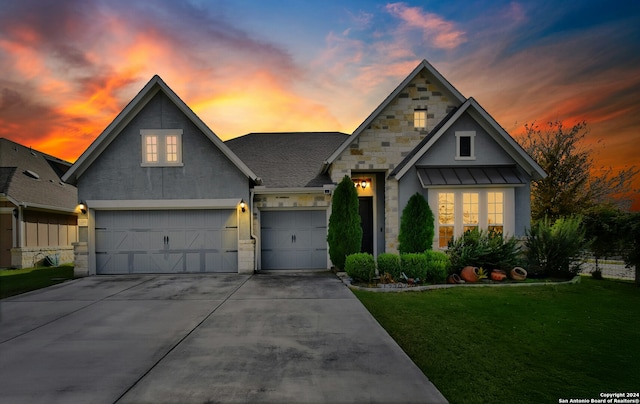 view of front of home with a garage and a lawn