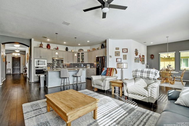 living room with ceiling fan, dark wood-type flooring, and a textured ceiling