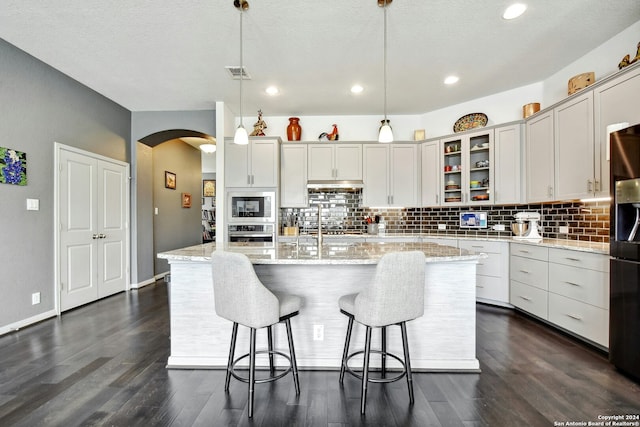 kitchen with a kitchen island with sink, hanging light fixtures, and dark hardwood / wood-style floors