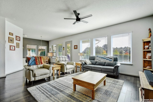 living room with ceiling fan with notable chandelier, a textured ceiling, and dark hardwood / wood-style flooring