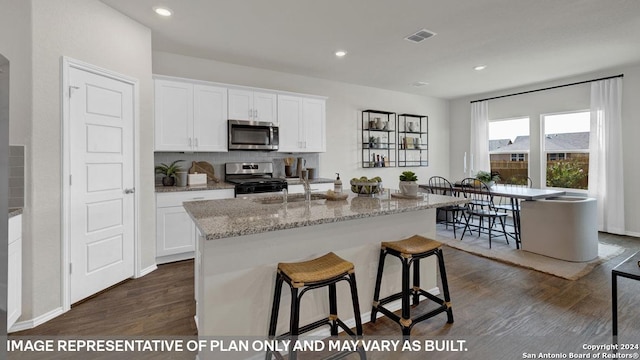 kitchen featuring a kitchen island with sink, dark hardwood / wood-style flooring, white cabinets, and appliances with stainless steel finishes