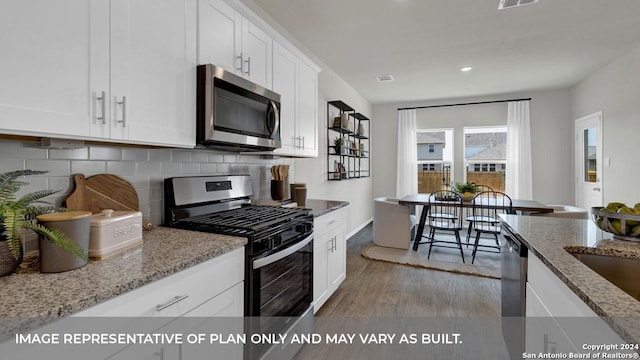 kitchen with light stone counters, white cabinetry, stainless steel appliances, and dark hardwood / wood-style floors