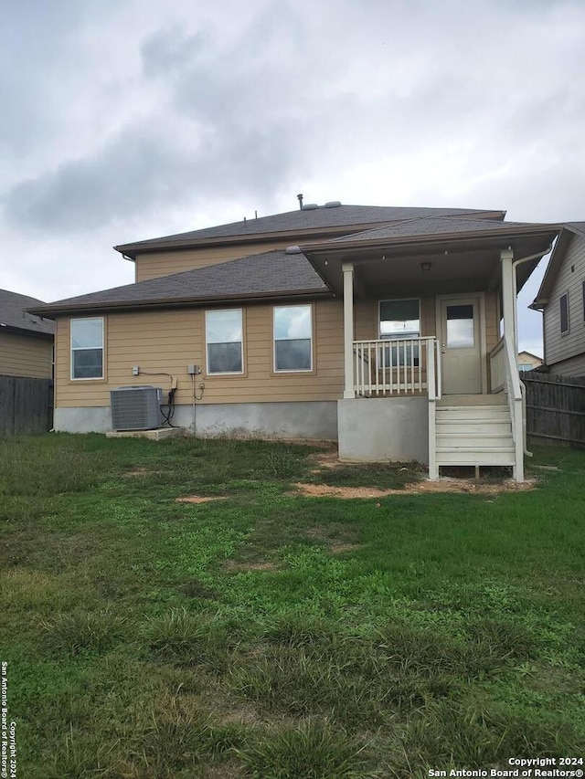 rear view of house with a lawn, a porch, and central AC