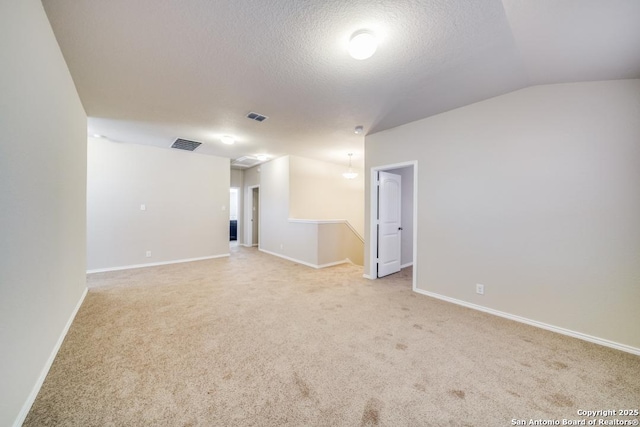 carpeted empty room featuring a textured ceiling and vaulted ceiling