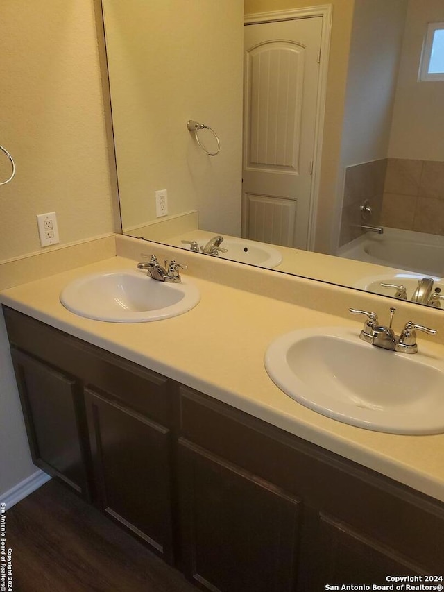 bathroom with a bathing tub, hardwood / wood-style floors, and vanity