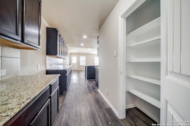 kitchen featuring dark hardwood / wood-style floors, dark brown cabinets, light stone countertops, and tasteful backsplash