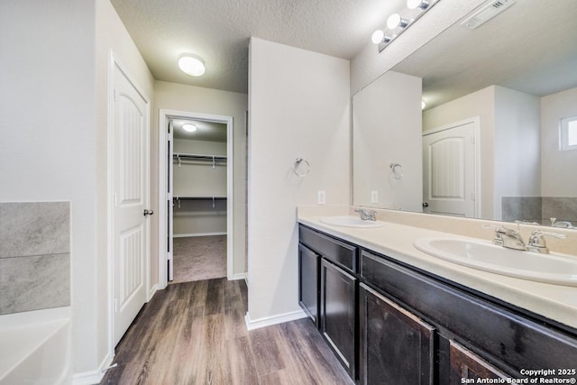 bathroom with a textured ceiling, vanity, a bathtub, and hardwood / wood-style floors