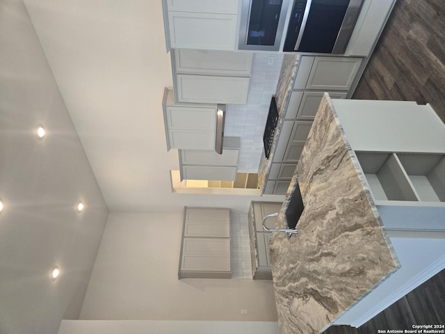 kitchen featuring backsplash, gray cabinets, and light stone counters