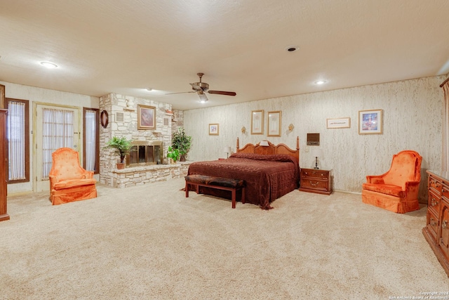 bedroom with ceiling fan, a fireplace, and light colored carpet