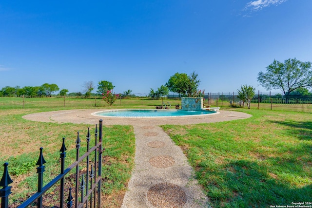 view of pool featuring a lawn and a rural view