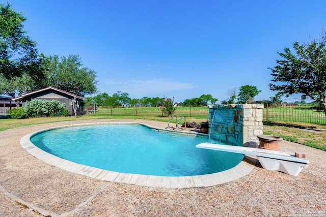 view of swimming pool featuring a lawn and a diving board