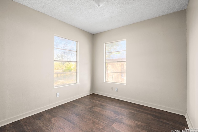 empty room with a textured ceiling and dark hardwood / wood-style floors