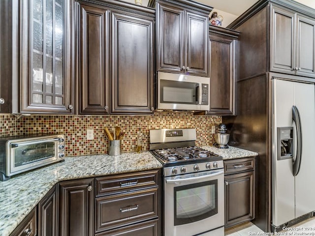 kitchen featuring backsplash, dark brown cabinets, light stone countertops, and stainless steel appliances