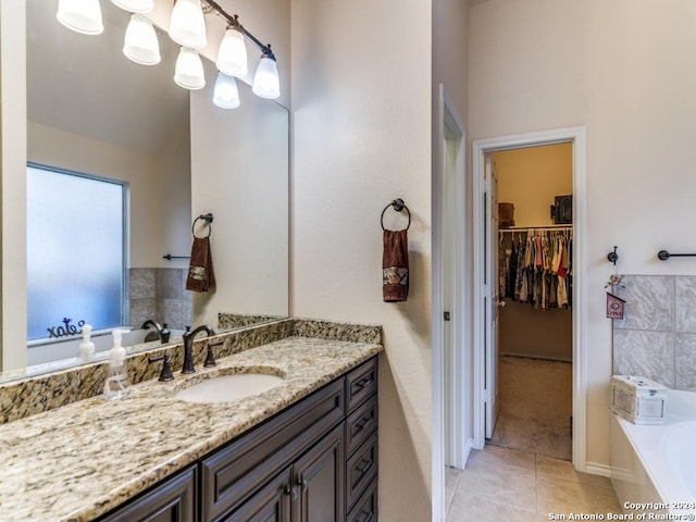 bathroom with a bathing tub, vanity, and tile patterned floors