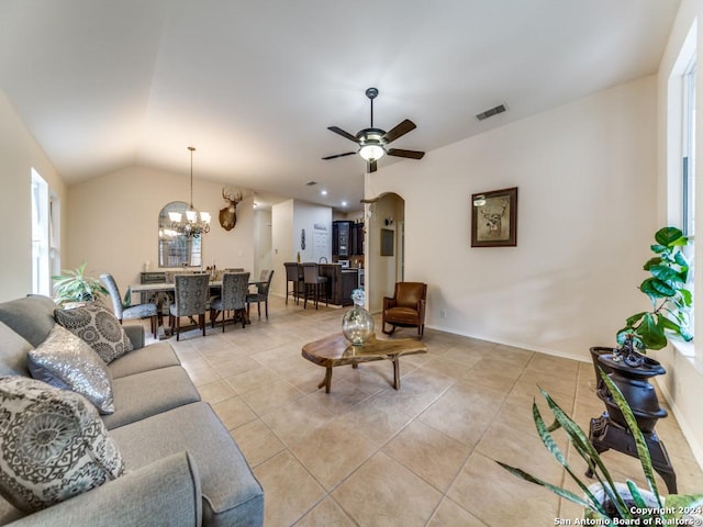 tiled living room with ceiling fan with notable chandelier and lofted ceiling