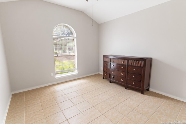 spare room with a wealth of natural light, light tile patterned floors, and lofted ceiling