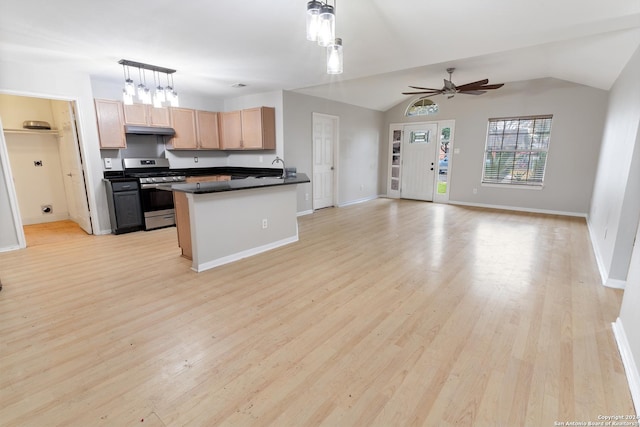 kitchen with light hardwood / wood-style floors, decorative light fixtures, stainless steel gas range oven, and lofted ceiling