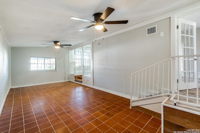 tiled spare room with a textured ceiling and ceiling fan