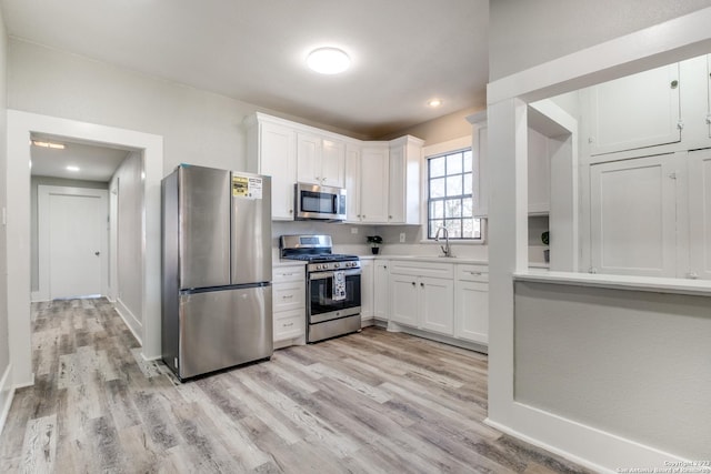 kitchen with stainless steel appliances, light hardwood / wood-style floors, sink, and white cabinets