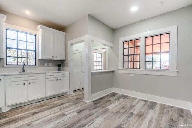 kitchen with sink, white cabinets, and light wood-type flooring