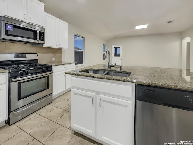 kitchen with decorative backsplash, appliances with stainless steel finishes, light stone counters, sink, and white cabinets