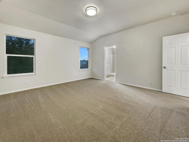 empty room with carpet flooring and vaulted ceiling