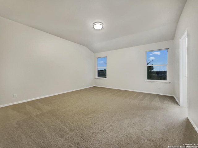 carpeted spare room with lofted ceiling