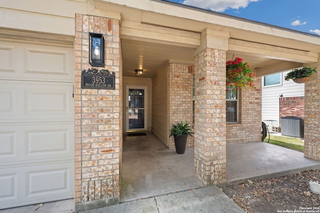 view of exterior entry featuring central AC unit and a garage