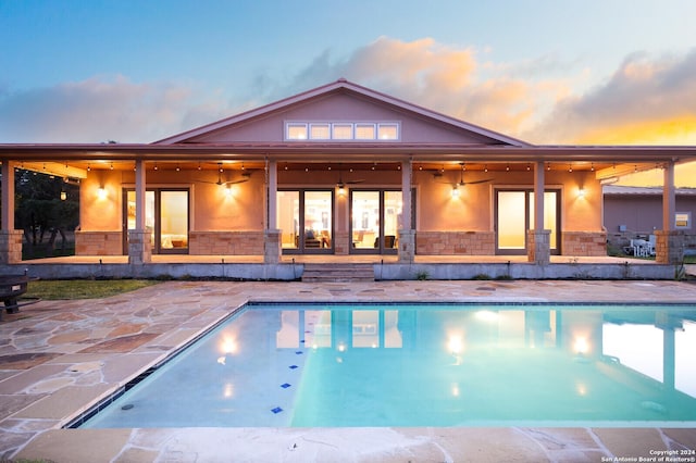 pool at dusk featuring a patio area and ceiling fan