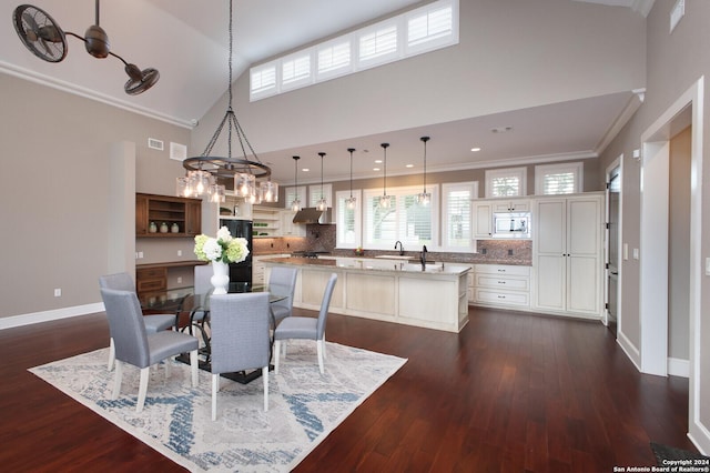 dining room with dark wood-type flooring, high vaulted ceiling, sink, ornamental molding, and a notable chandelier