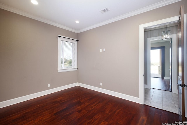 unfurnished room featuring crown molding, dark hardwood / wood-style floors, and an inviting chandelier