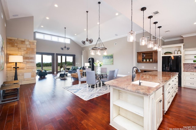 kitchen featuring light stone countertops, a large island, dark wood-type flooring, and hanging light fixtures