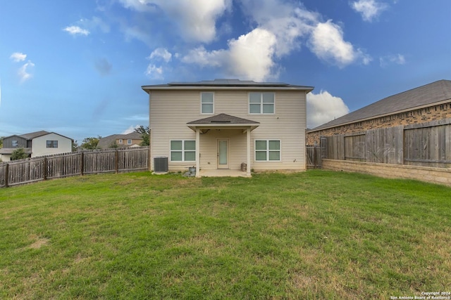 rear view of house with central AC unit, solar panels, a patio area, and a yard